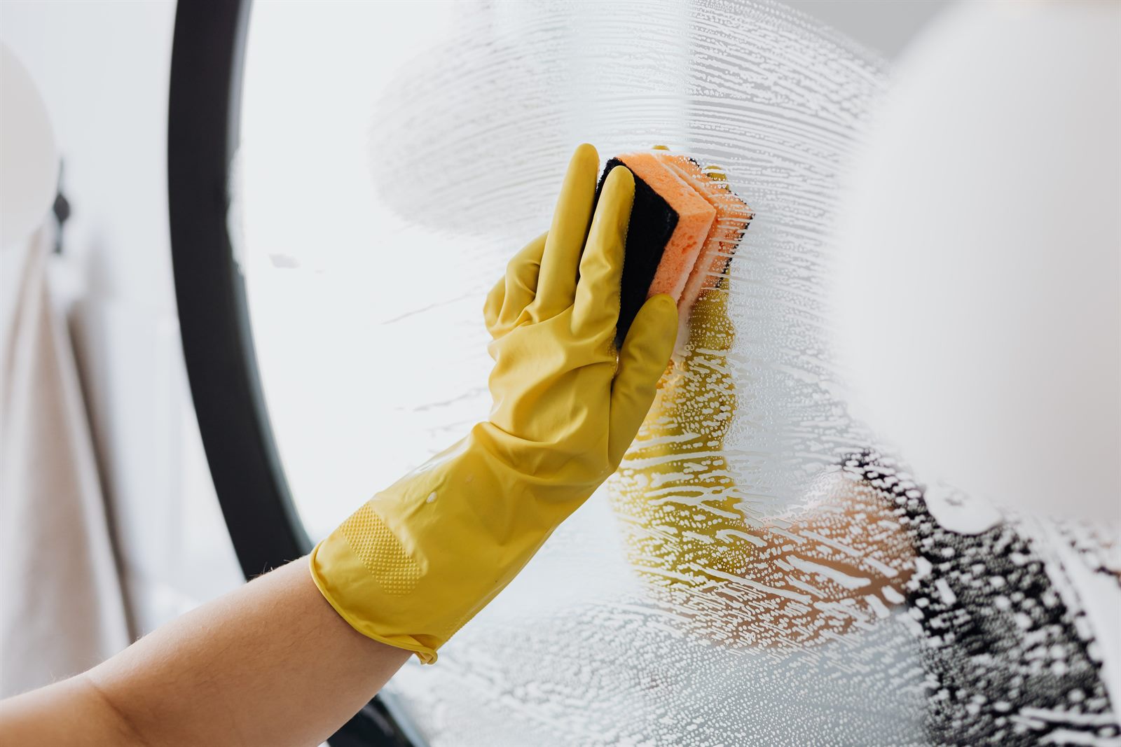 Gloved hand wiping a mirror spotless during a move-out cleaning in Greater Boston
