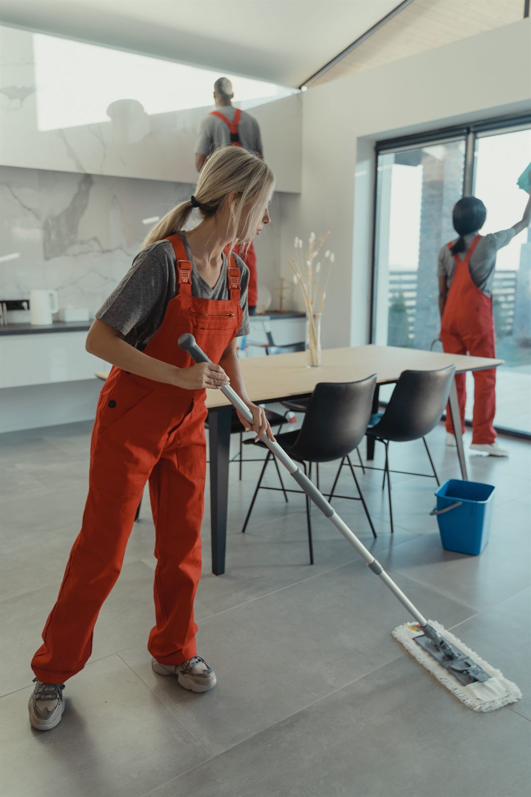 Cleaner mopping a tile floor in a dining area during a turnover cleaning