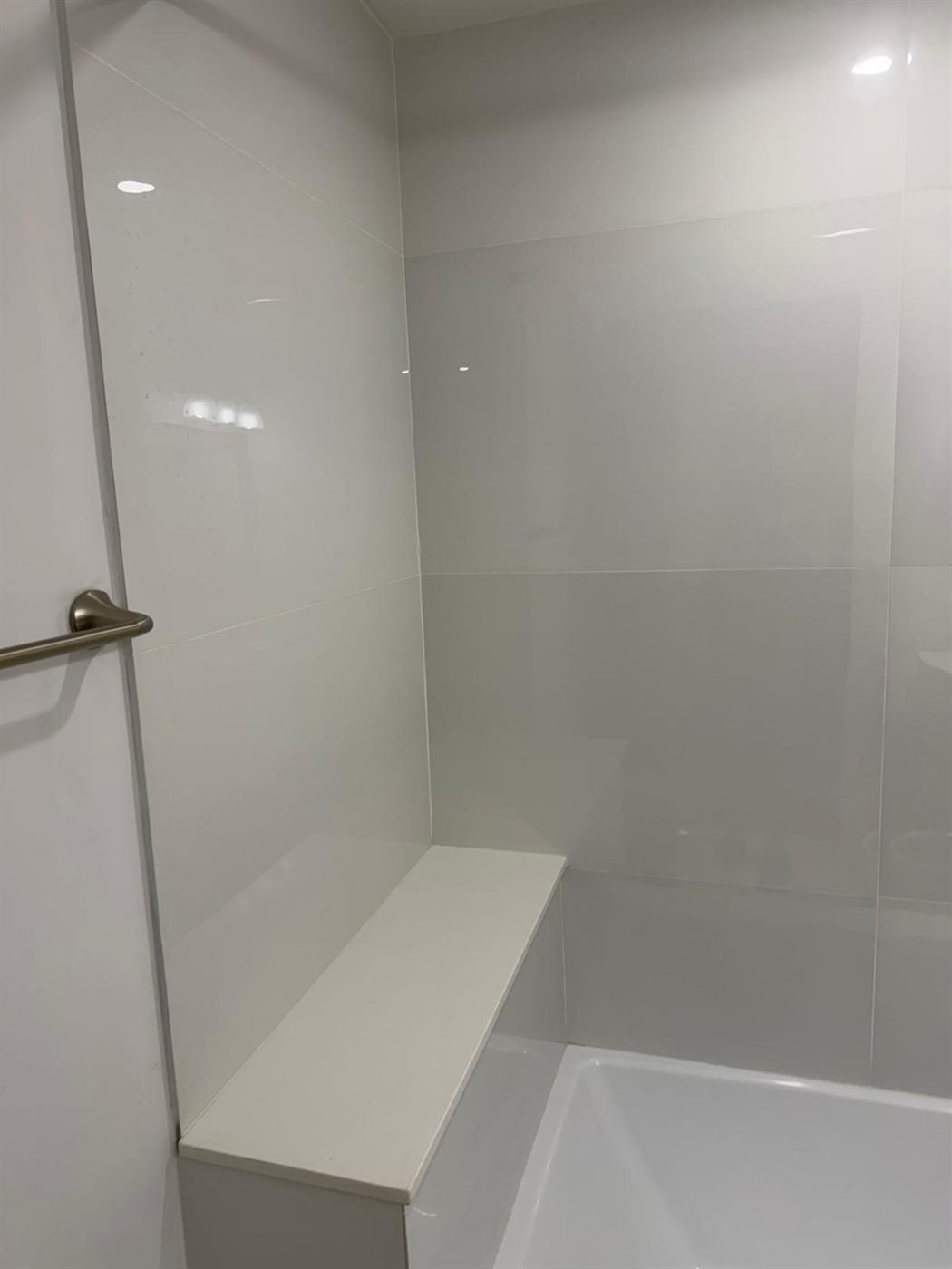 Clean tiled walk-in shower with a bench after a turnover cleaning